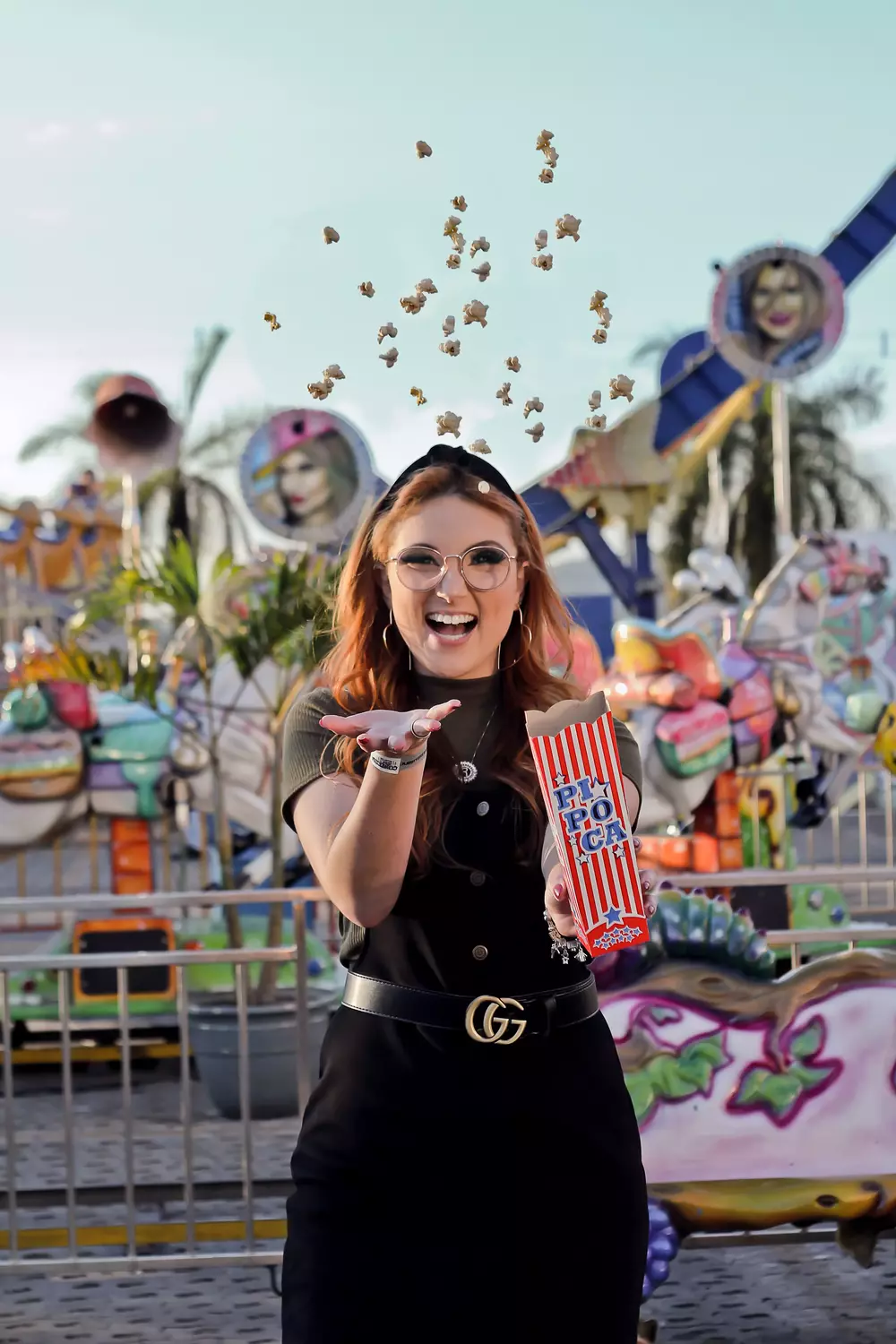 A lady throwing a handful of popcorn in the air at a fairground.
